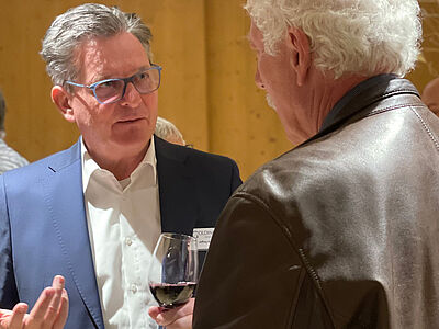 Zwei ältere Herren besprechen mit Wein in der Hand.